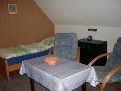 Gemütliches Wohn/Schlaf mit Bett, Tisch und zwei Stühlen.